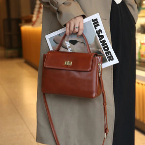 Bolsa Victoire caramelo usada na mão com trench coat | Vivièn